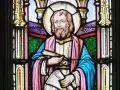 Witraż przedstawia świętego Łukasza z księgą i zwojem, symbolizując jego rolę jako ewangelisty i pisarza.