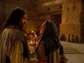 Scena z Kany Galilejskiej: Jezus rozmawia z kobietą, w tle widać gości weselnych i świece.
