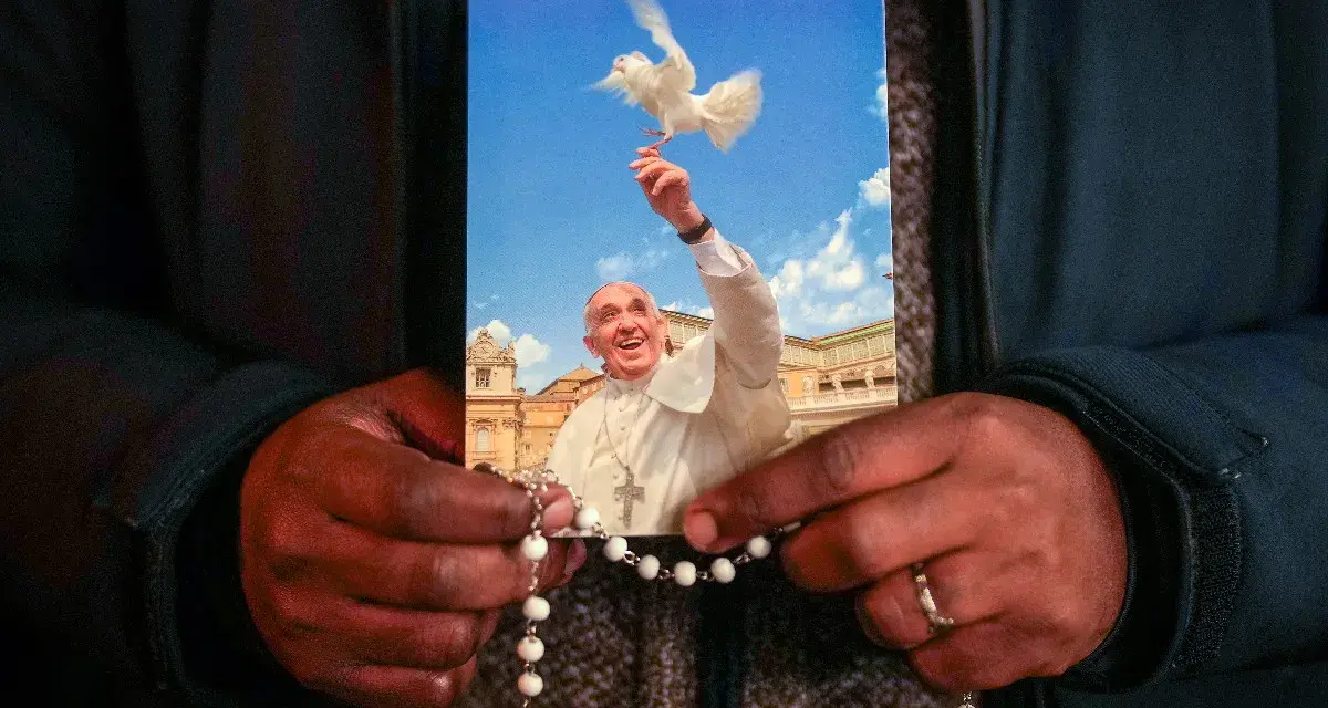 Dłonie trzymają obrazek z Papieżem Franciszkiem wypuszczającym gołębicę. To inspiracja z cytatów papieża franciszka.