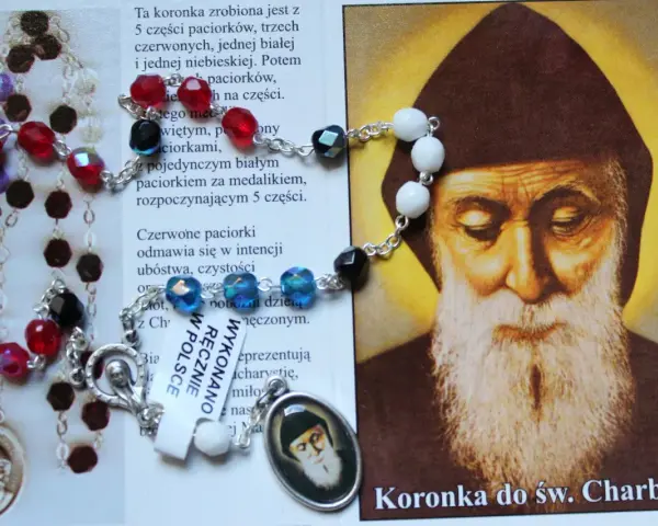 Koronka do św. Charbela z czerwonymi i białymi paciorkami, obok wizerunku świętego.