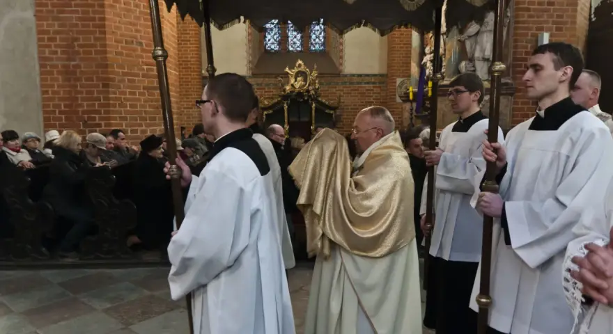 Uroczysta procesja w kościele, kapłan niesie monstrancję okrytą złotym welonem. To symboliczna rezurekcja.