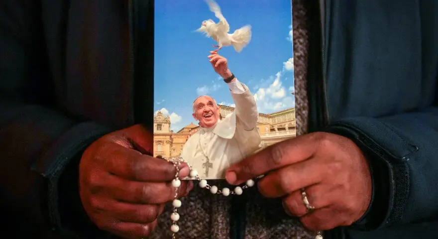 Dłonie trzymają obrazek z Papieżem Franciszkiem wypuszczającym gołębicę. To inspiracja z cytatów papieża franciszka.