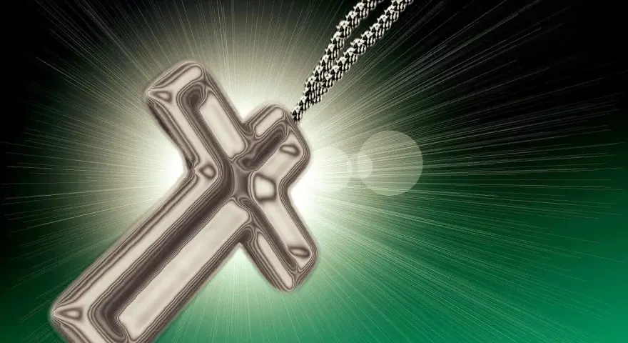 Srebrny krzyż na łańcuszku, emanujący światłem, symbol nadziei i wiary, jak w psalmie 62.