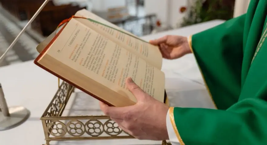 Kapłan w zielonej szacie czyta księgę podczas mszy żałobnej.