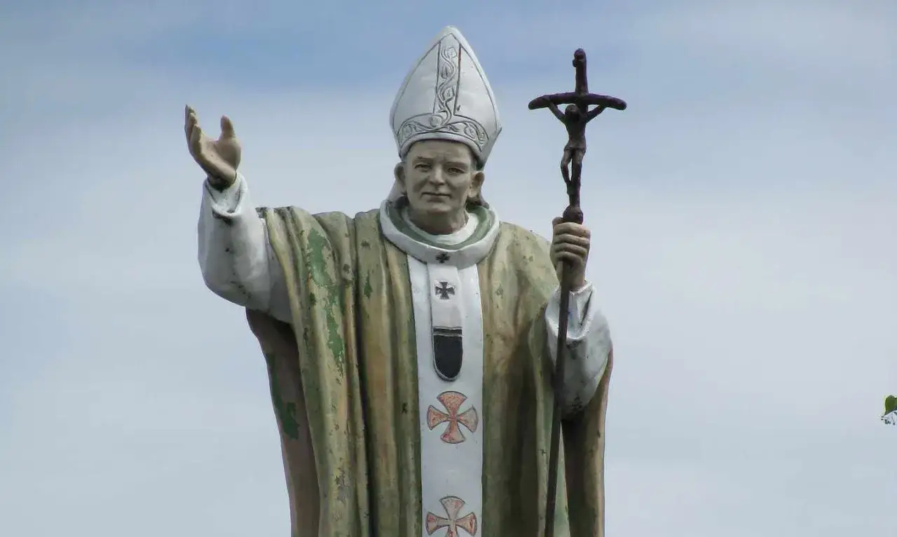 Pomnik Jana Pawła II z podniesioną ręką i krzyżem. Zastanawiamy się, ile języków znał Jan Paweł II, który przemawiał do świata.